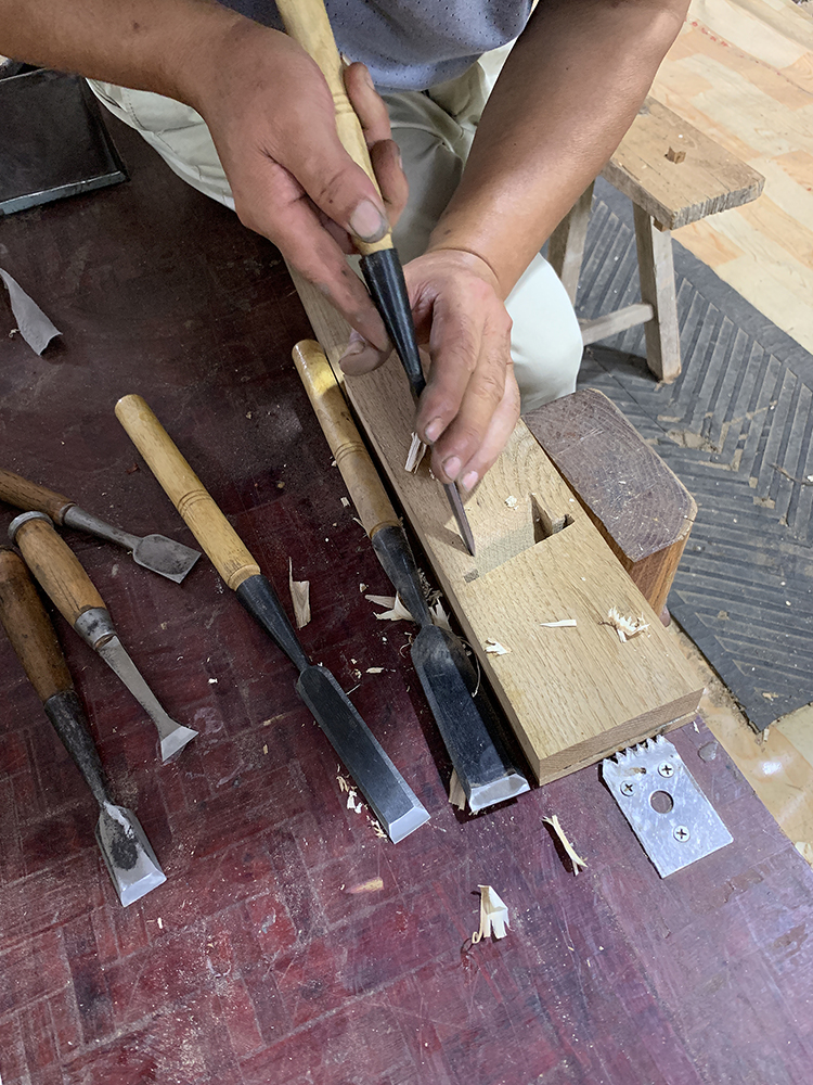 时,左手握凿(刃口向内),右手握斧敲击,从榫孔的近端逐渐向远端凿削,先